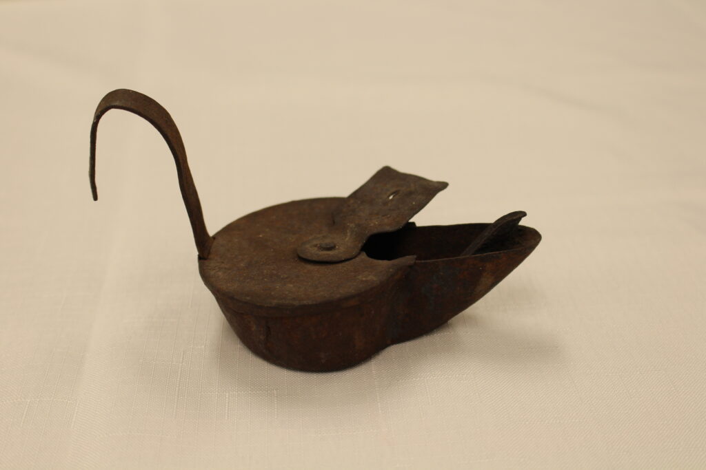 A metal Betty lamp with a large curved handle